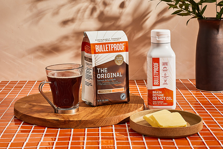 Bulletproof The Original coffee, Brain Octane Oil and butter on countertop by cup of black coffee