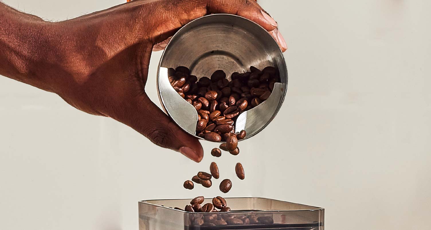 Pouring coffee beans into a grinder