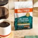 Bulletproof The High Achiever™ coffee bag next to hand holding brewed mug